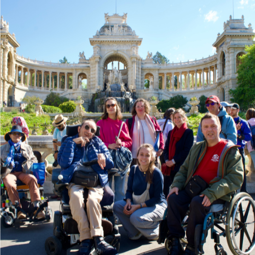 Photo de groupe de personnes à mobilité réduite en balade devant le parc Longchamp